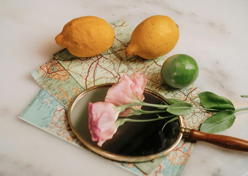 travel maps on a table with a magnifying glass, roses, and fruit